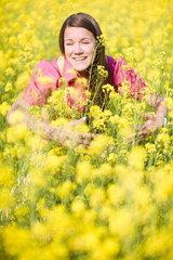 Naklejka na ściany i meble Pretty smiling girl relaxing on green meadow full yellow flowers