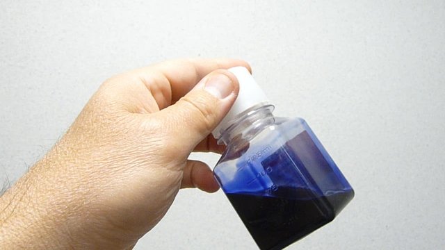 hand holding bottle with blue solution