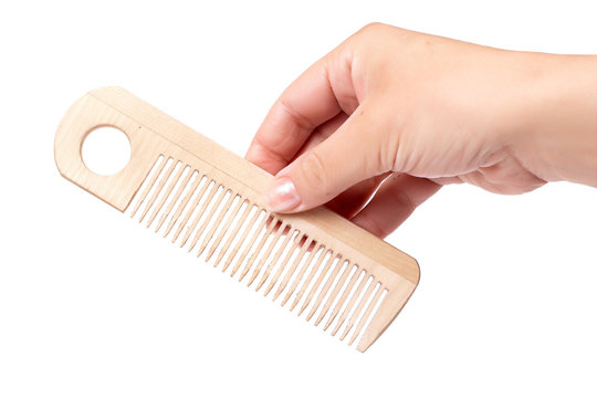 Woman's hand with wooden comb isolated on white.