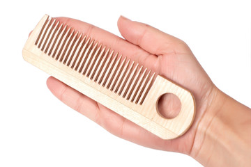 Woman's palm with wooden comb isolated on white.