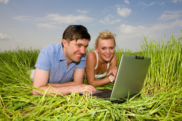 Casual happy couple on laptop computer outdoors.