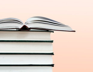 Open book and pile of books isolated on pink background