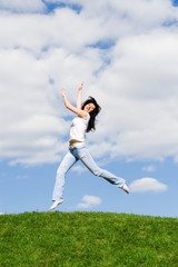 Fototapeta na wymiar pretty young woman is jumping on green grass