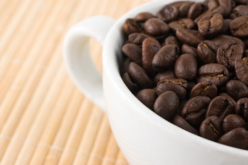 coffe grains and cup on bamboo mat