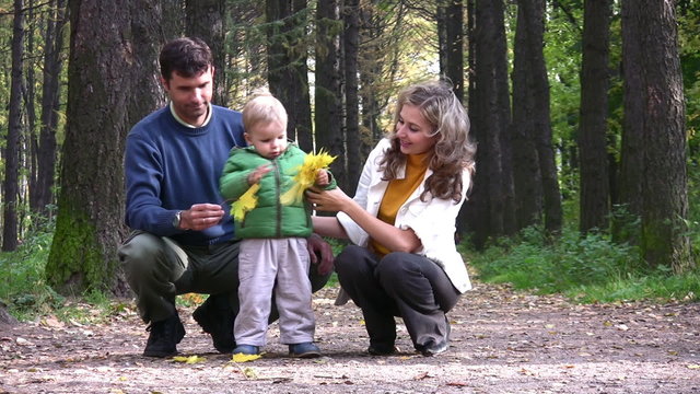 parents with boy with leaves in park