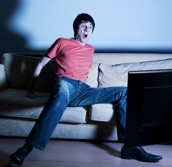 jeune homme choqué regardant la tv