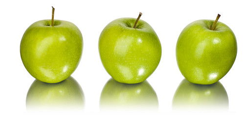 Three green apples with water drops reflecting on a mirror