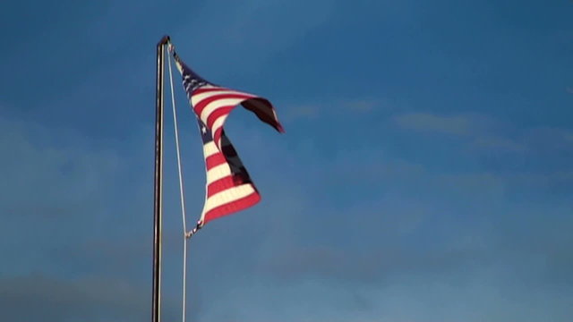 American flag proudly blows in wind against blue sky - HD