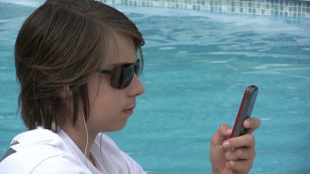 ado tapant un texto sur son portable au bord de l'eau