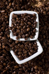 Two square bowls full of coffee beans, view from above