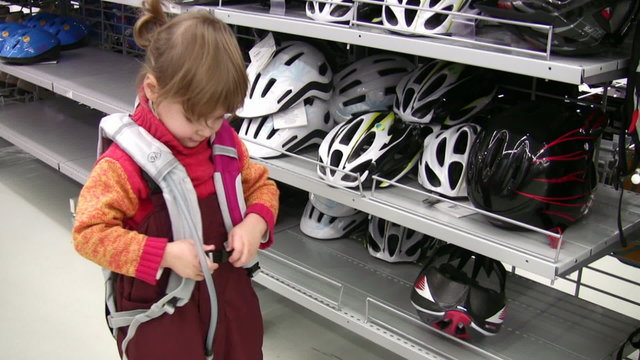 little girl with knapsack in shop, bicycle helmets