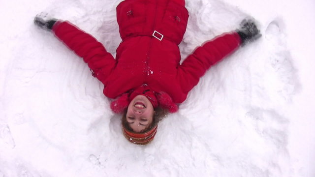 woman lies on snow with hands as wings