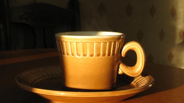 Cup with hot coffee on saucer. Time lapse. Moving shadow.