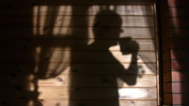 Shade of person drinking from mug on wall