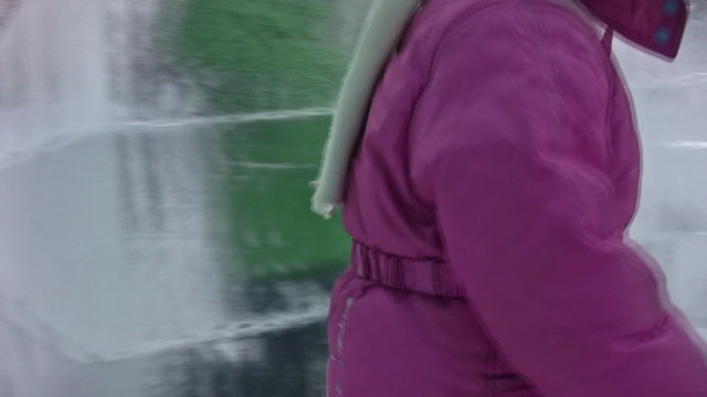 Small girl goes along icy building labyrinth