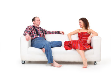 Barefoot man and woman sit on white leather sofa