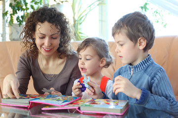 Mother and children play with jigsaw puzzle