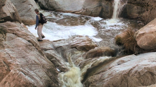 Hiker crossing waterfall - HD