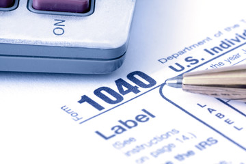 1040 Tax form with pen and calculator with blue overlay