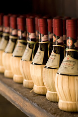 Chianti wine bottles on a rack - obrazy, fototapety, plakaty
