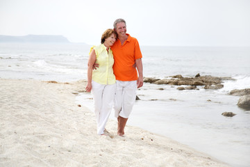 beautiful mature couple walking along the beach