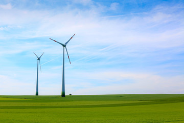 Fototapeta na wymiar Wind turbines farm in green field over cloudy sky
