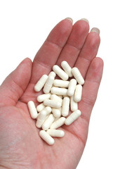 Many white tablets in a hand on a white background