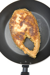 fried fish steak on griddle closeup