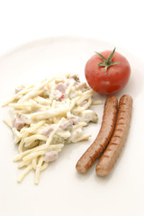 Schinkenwuerste und Nudelsalat mit einer Tomate