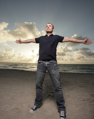 Fototapeta na wymiar Man on the beach with arms outstretched