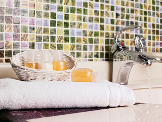 White towel with bottles of shampoo near a sink in a bathroom.