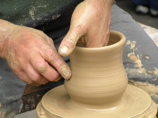 Potter working with clay bowl on potter's wheel