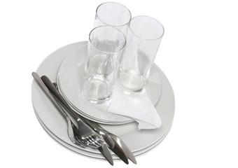 Pile of white plates, glasses with forks, spoons,silk napkin.