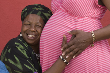 grandmother holding daughter's pregnant belly