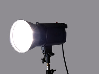 Studio monolight flash unit firing against gray background