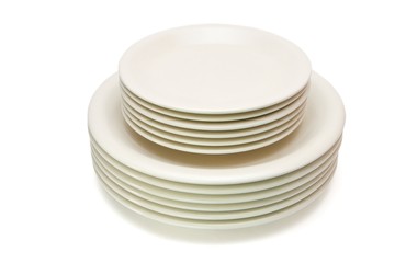 Stack of plain beige dinner plates and saucers isolated