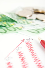 Euro banknotes and a pen on a graph