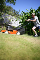 homme sénior avec tondeuse à gazon dans son jardin