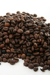 grains de café torréfié en tas sur fond blanc