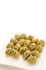 gruene Oliven auf einem weissen Teller