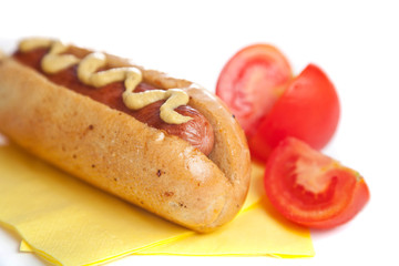 Hot dog with a tomato on a yellow napkin