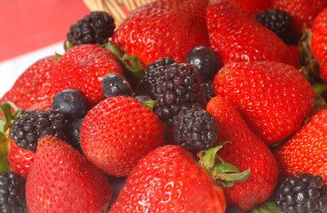 Fresh strawberries, blackberries and blueberries spilling out of