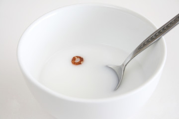 A bowl of milk with one peace of cereal floating in the milk.