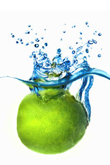 Fresh lime dropped into water with bubbles isolated on white