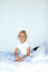 Naklejka premium Little girl sitting in bed with copyspace