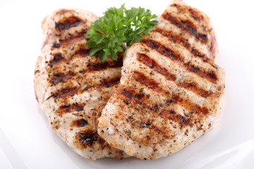 Grilled chicken breasts on a plate with fresh vegetables