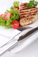 Grilled chicken breasts on a plate with fresh vegetables