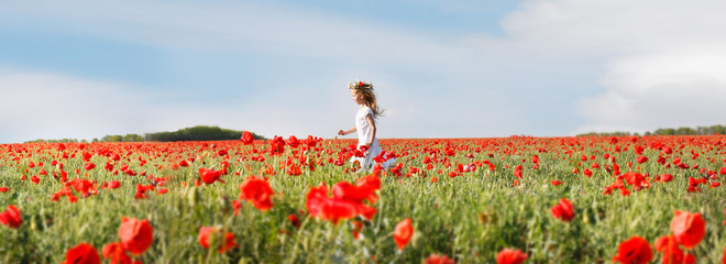 small girl in white dress running in poppy field