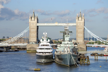 Naklejka premium HMS Belfast and a luxury yacht moored before with Tower Bridge