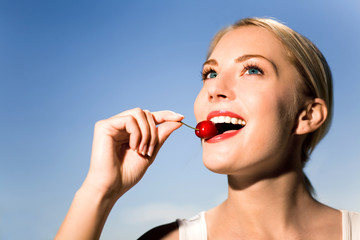 Young woman eating cherry